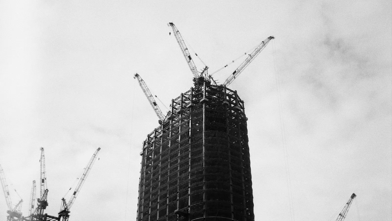 A tall building under construction with cranes on top