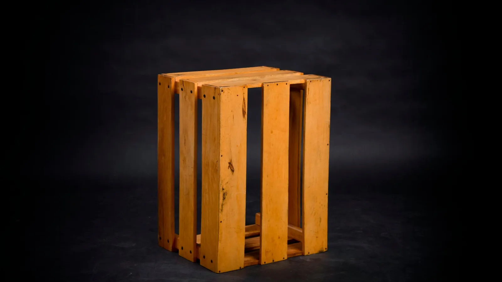 A tall wooden crate standing upright on a dark floor