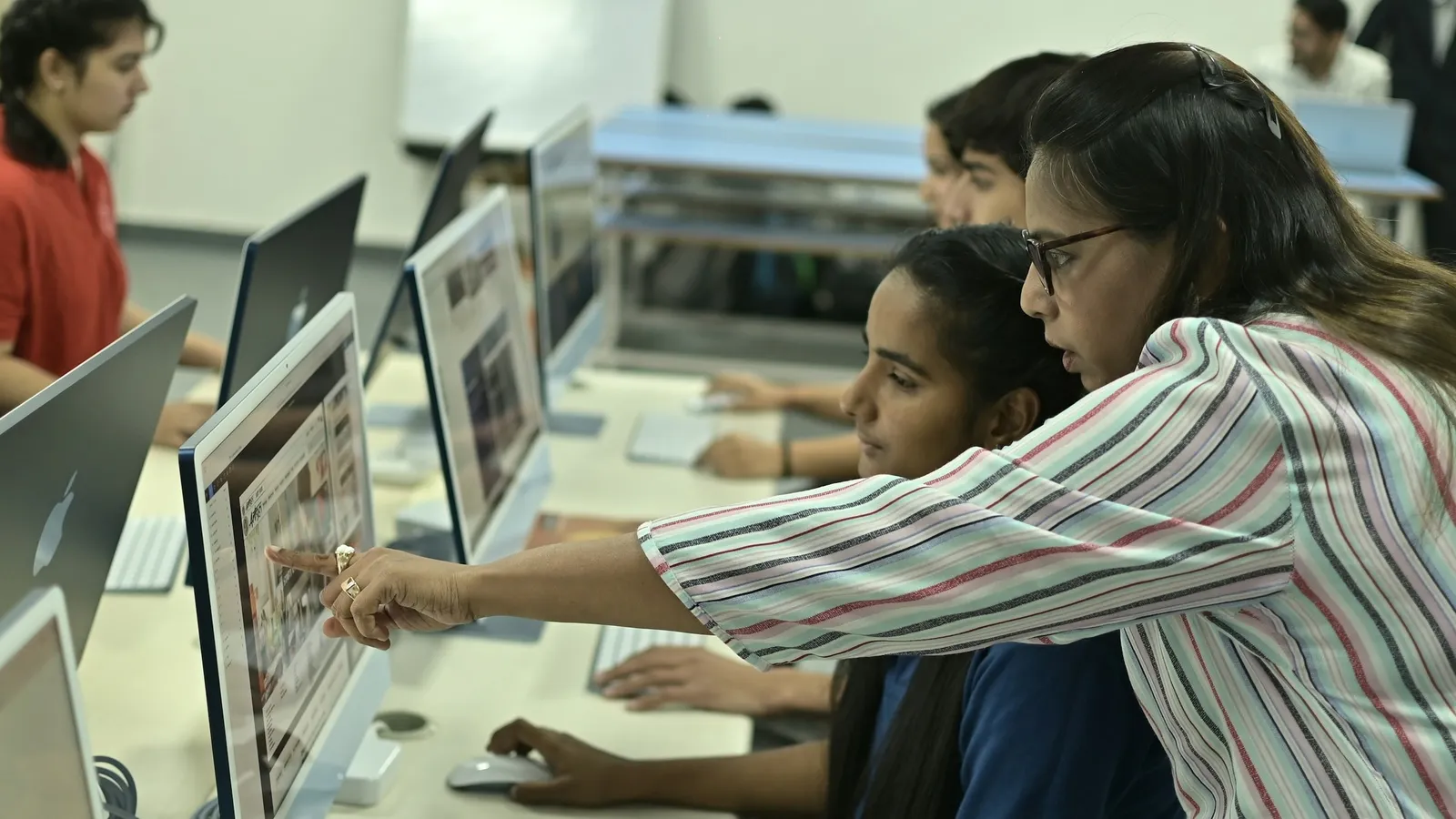 A teacher helping students at computers in a school lab