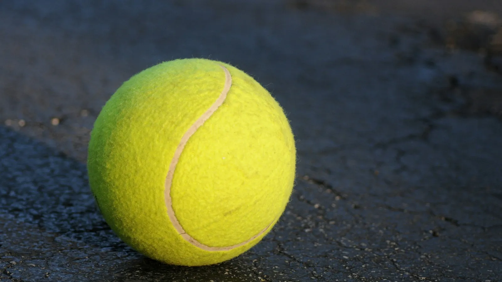 A tennis ball on a dark court