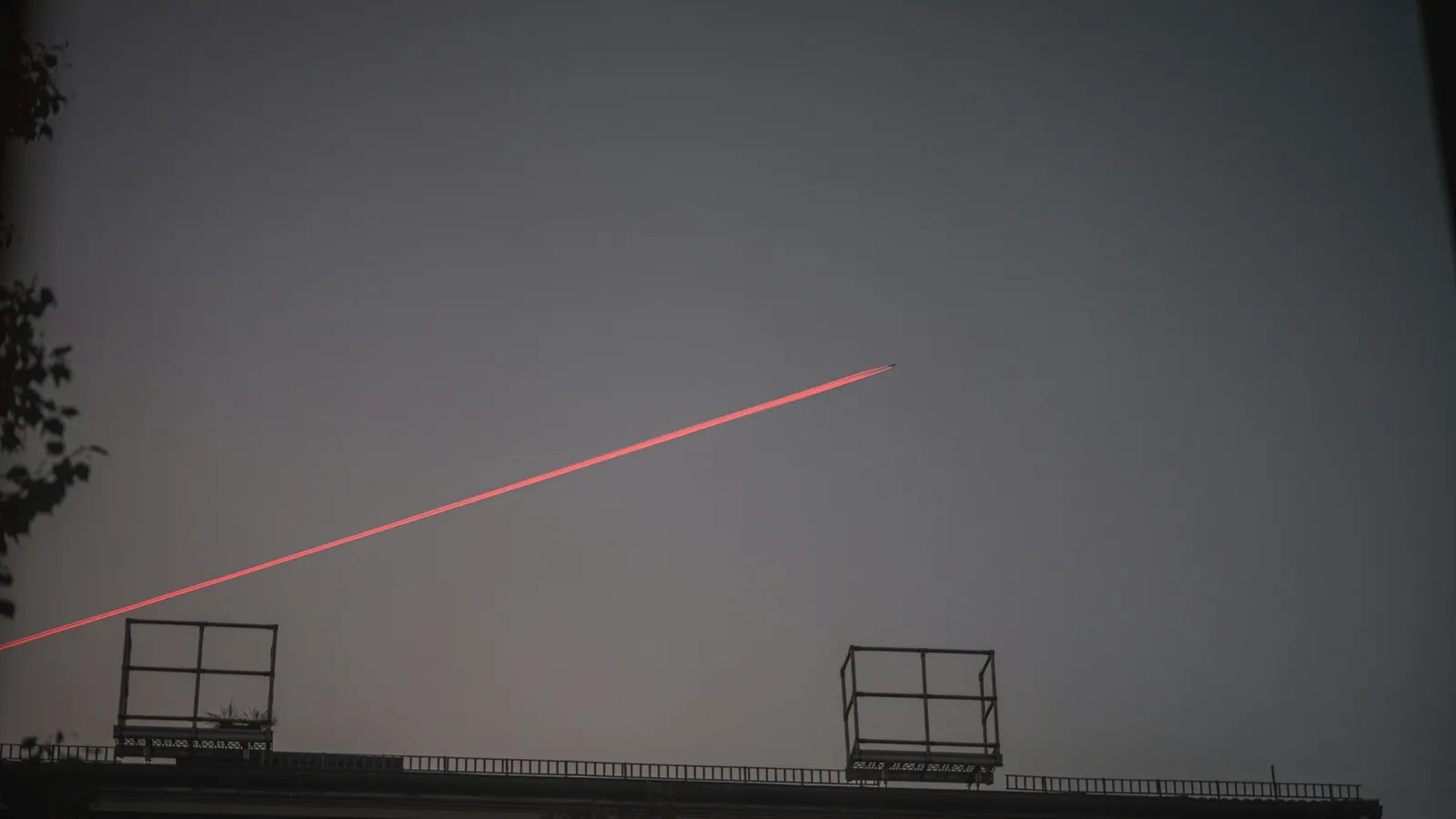 A thin red laser beam crossing a dim room