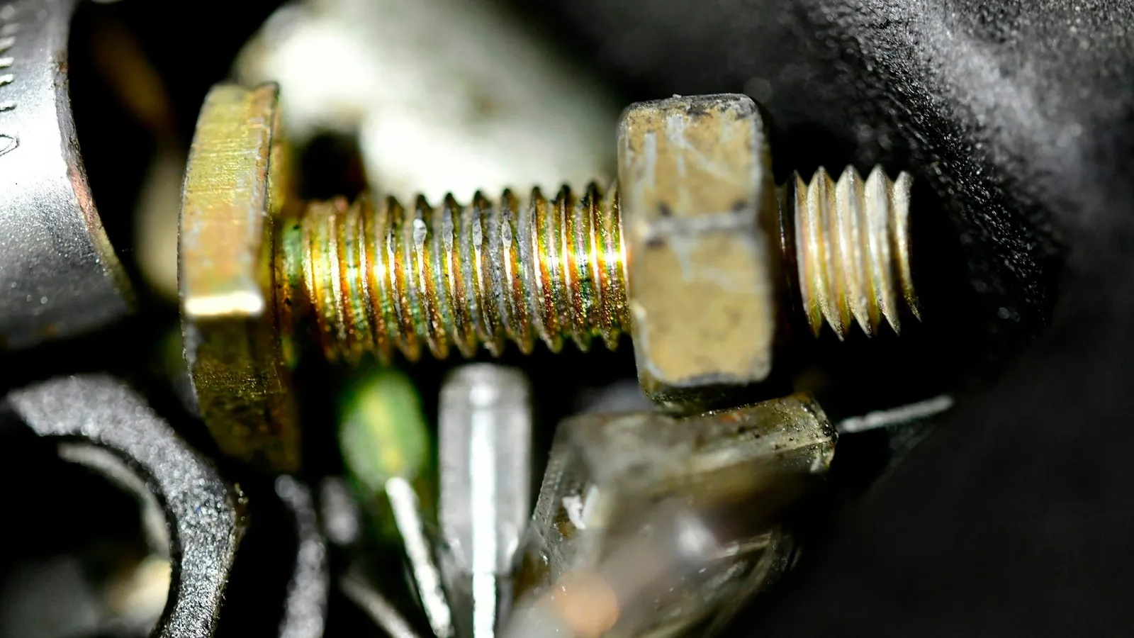 A threaded steel bolt and nut among machine parts