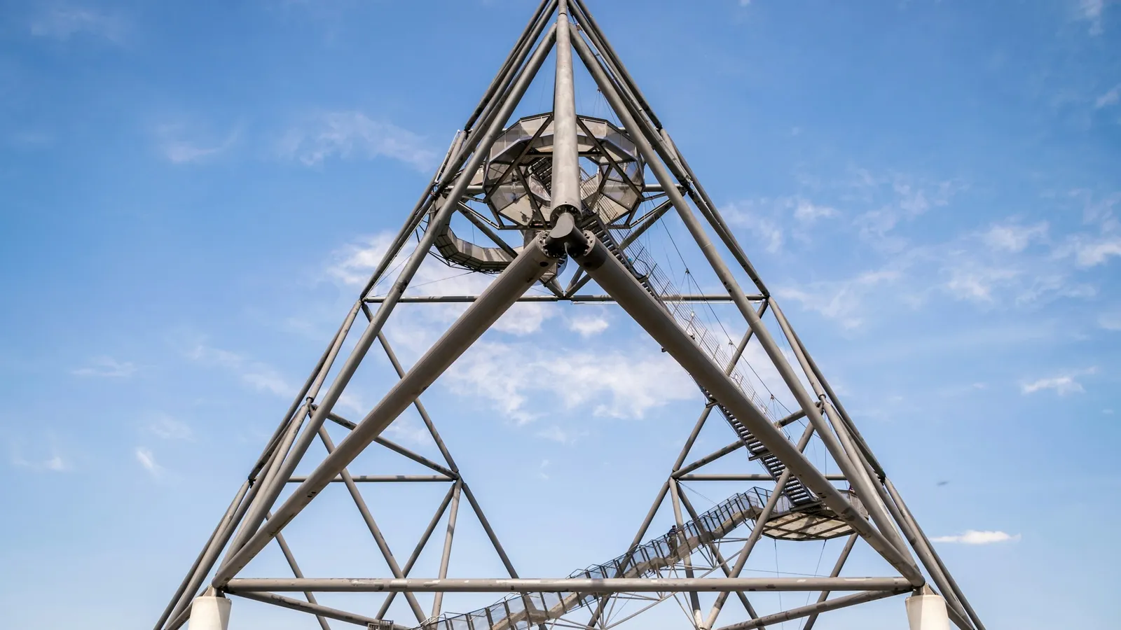 A triangular steel lattice tower against a blue sky