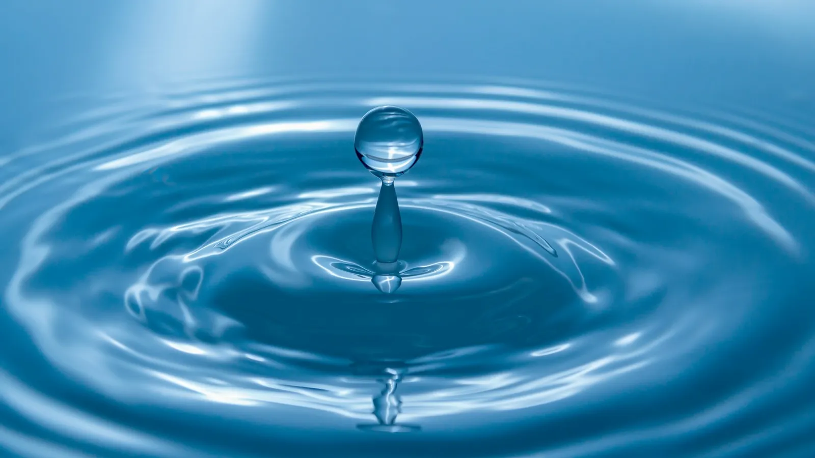 A water drop splashing into still blue water