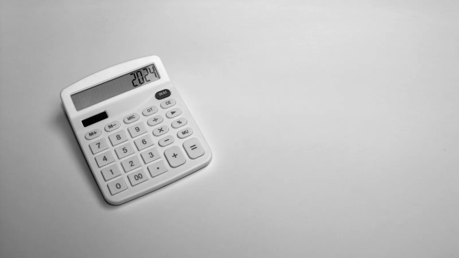 A white calculator on a grey surface