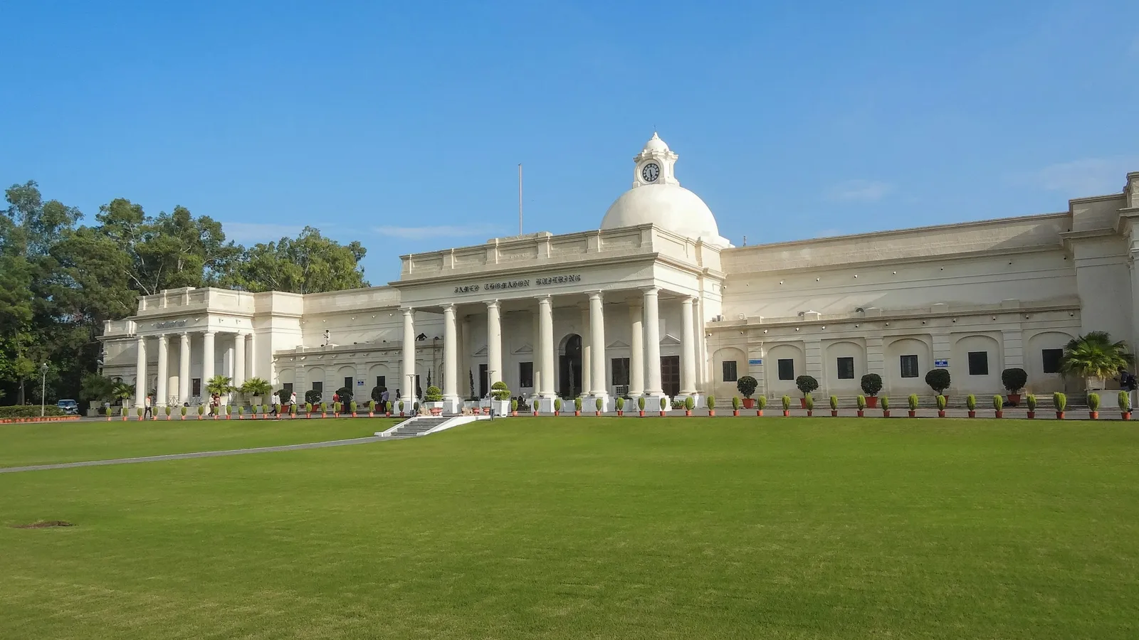 A white colonial-style college building behind a green lawn