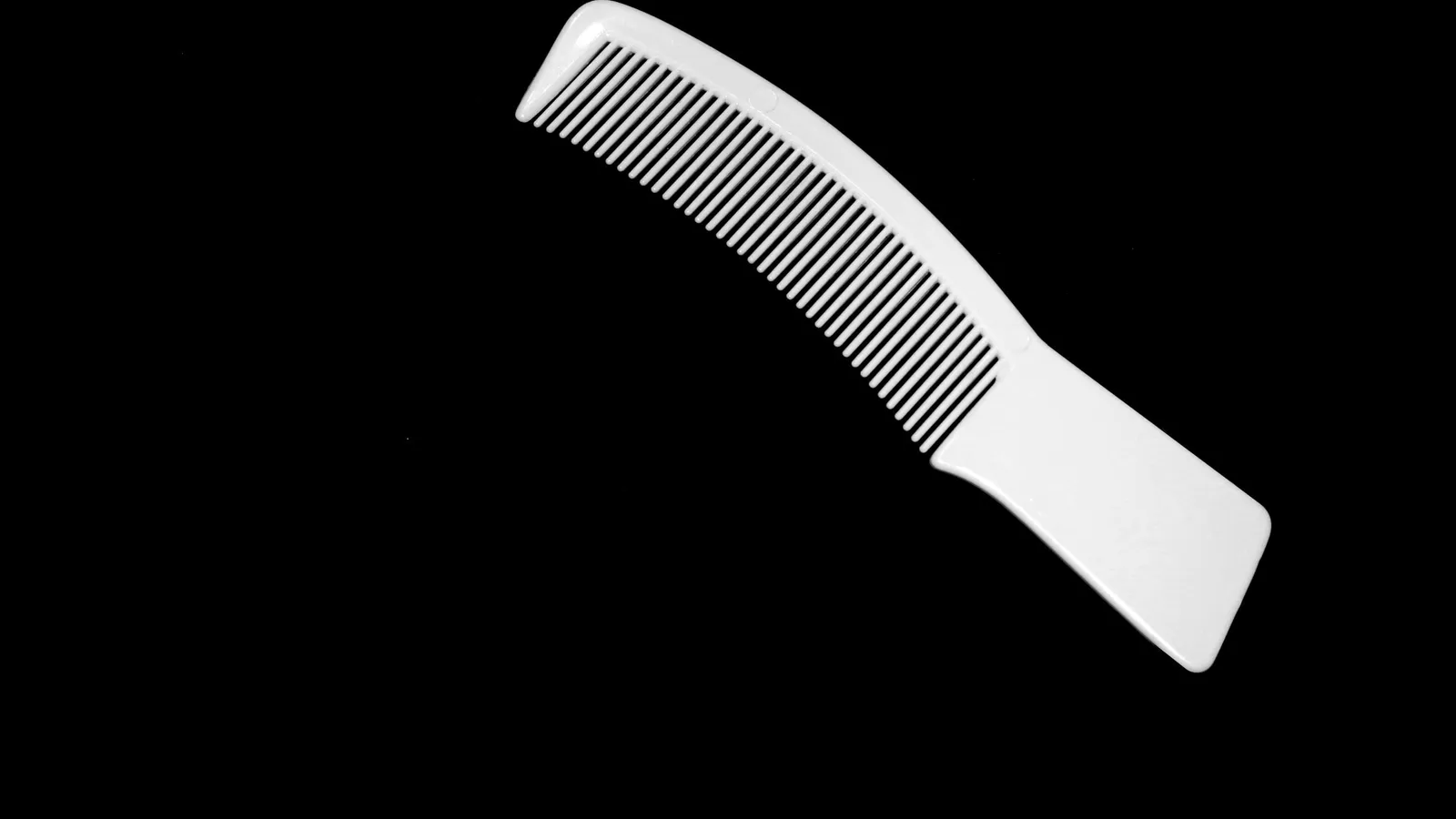 A white plastic comb on a black background