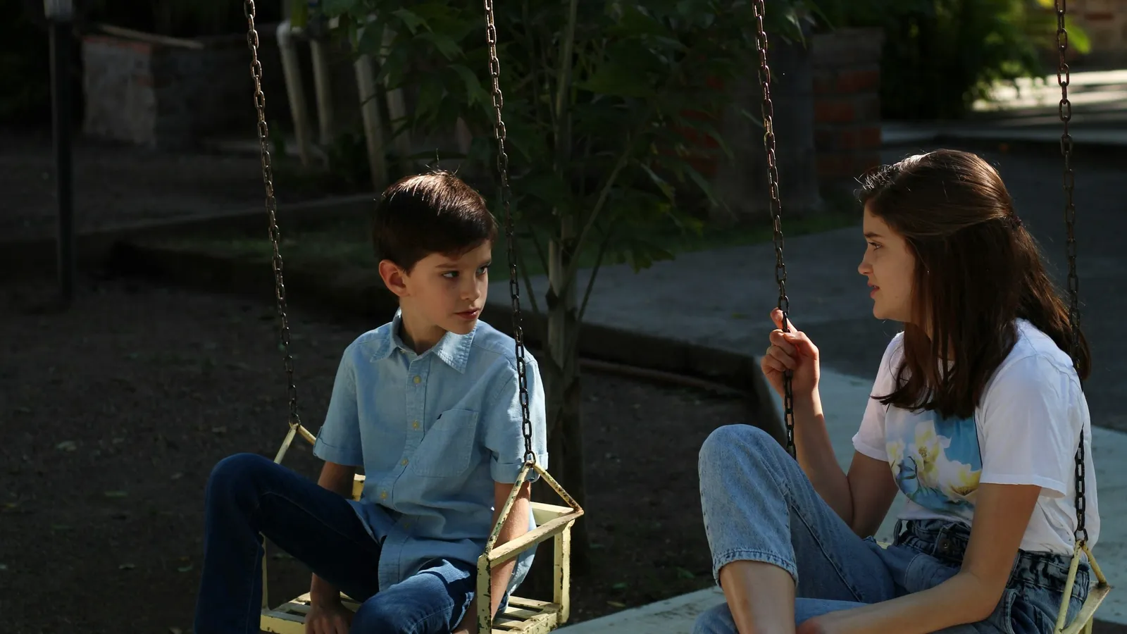 A woman and a boy sitting and talking together outdoors in the evening