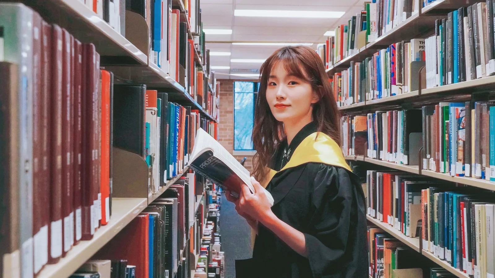 A woman in a library holding a book