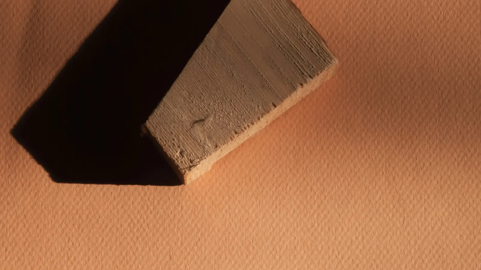 A wooden wedge block on an orange surface