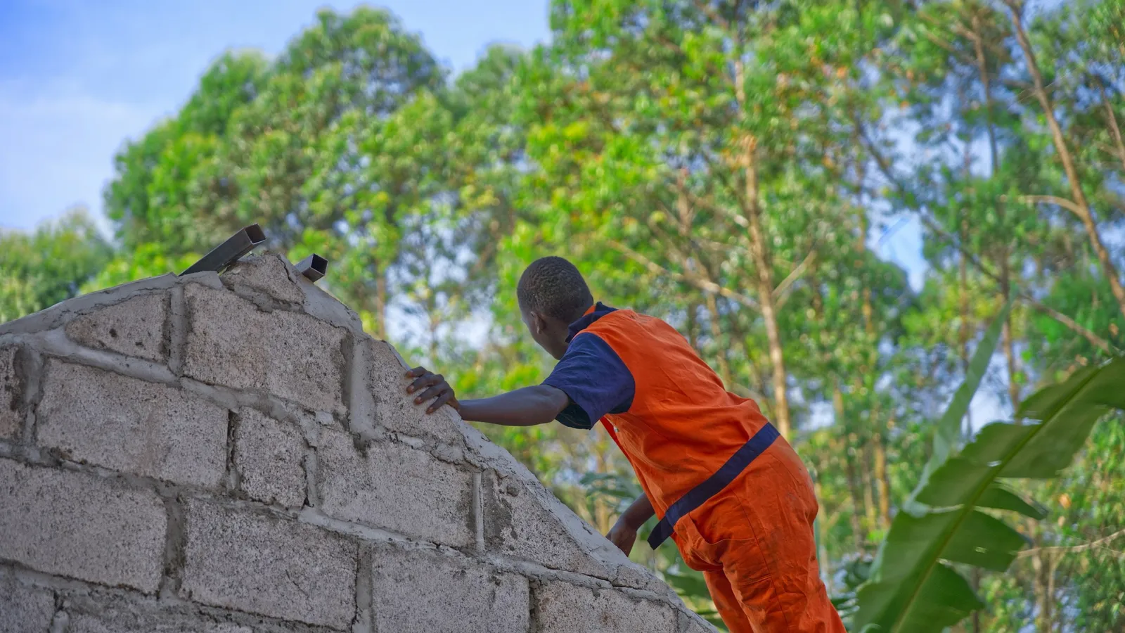 A worker laying bricks on a wall
