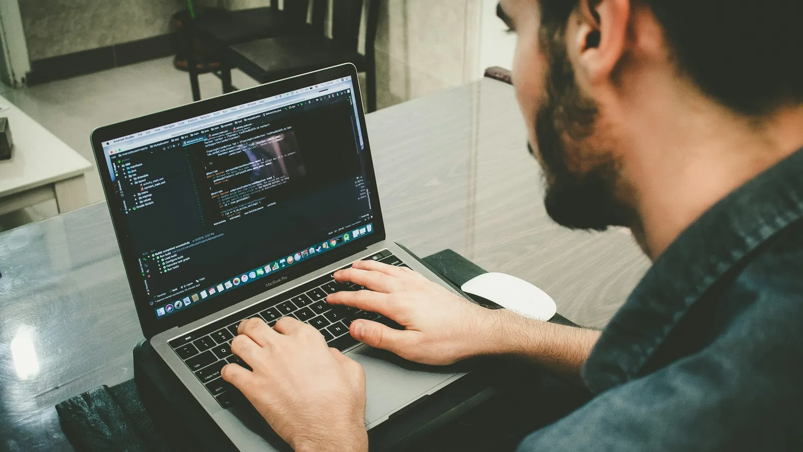 A young man typing code on a laptop