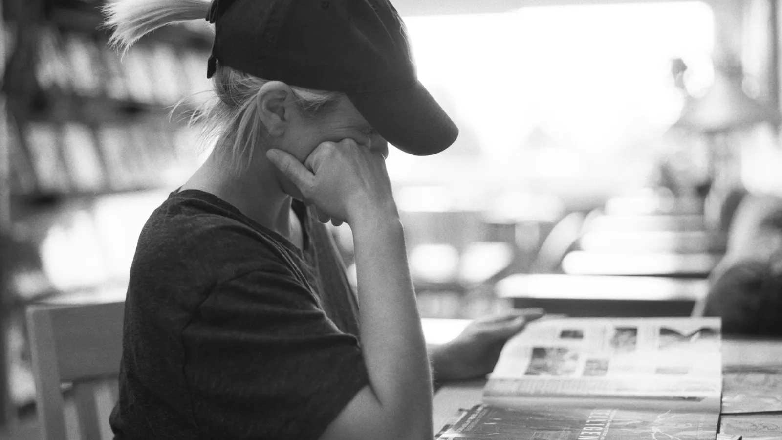 A young person in a cap resting their head on one hand