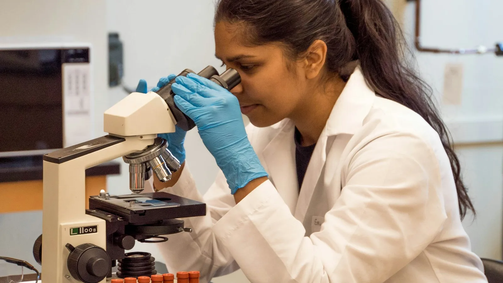 A young scientist looking into a microscope in a lab
