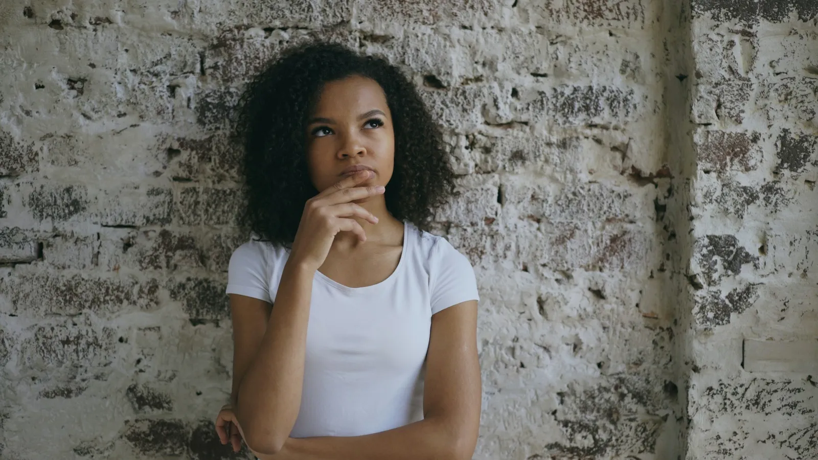 A young woman with her hand on her chin, thinking