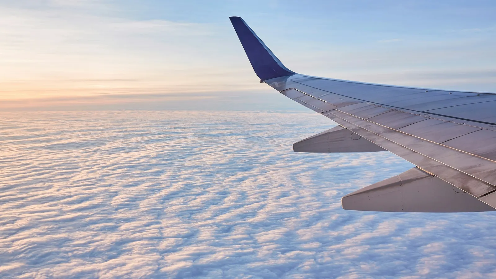 An aircraft wing above a layer of clouds