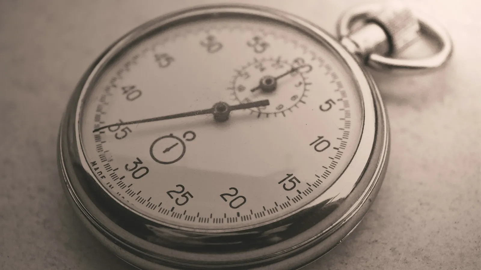 An analogue stopwatch lying on a grey surface