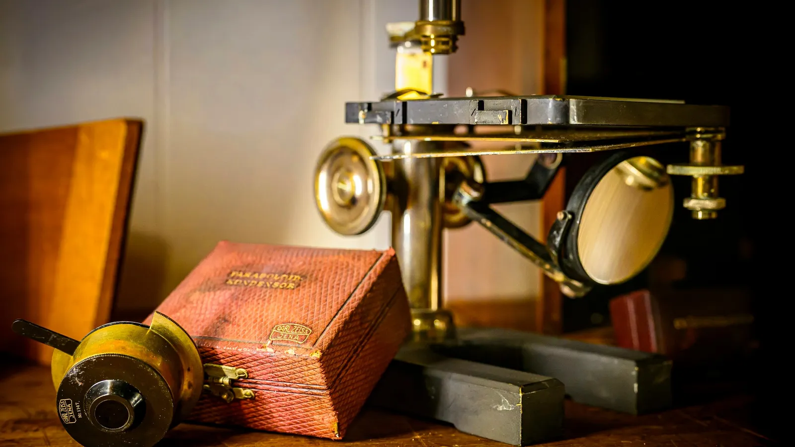 An antique brass microscope on a wooden desk