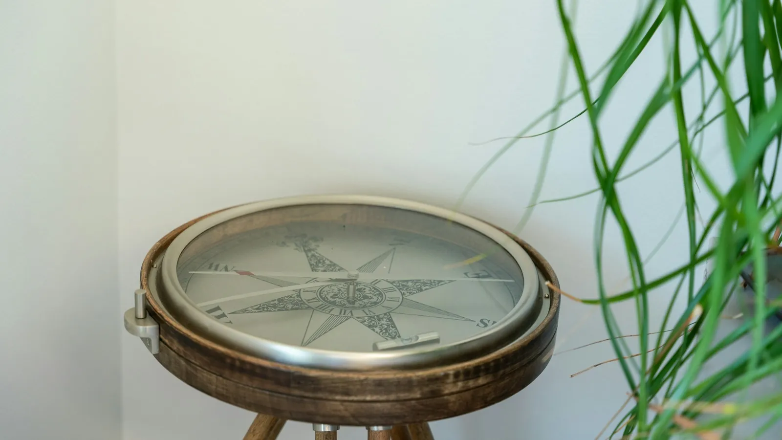 An antique compass on a wooden tripod stand