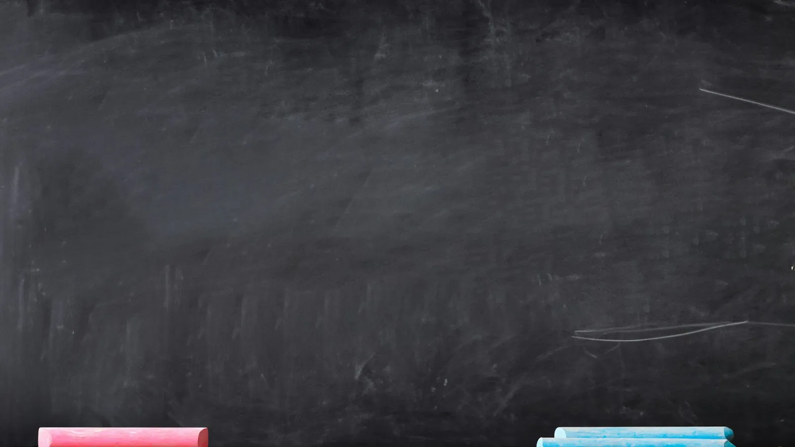 An empty chalkboard with coloured chalk on the ledge