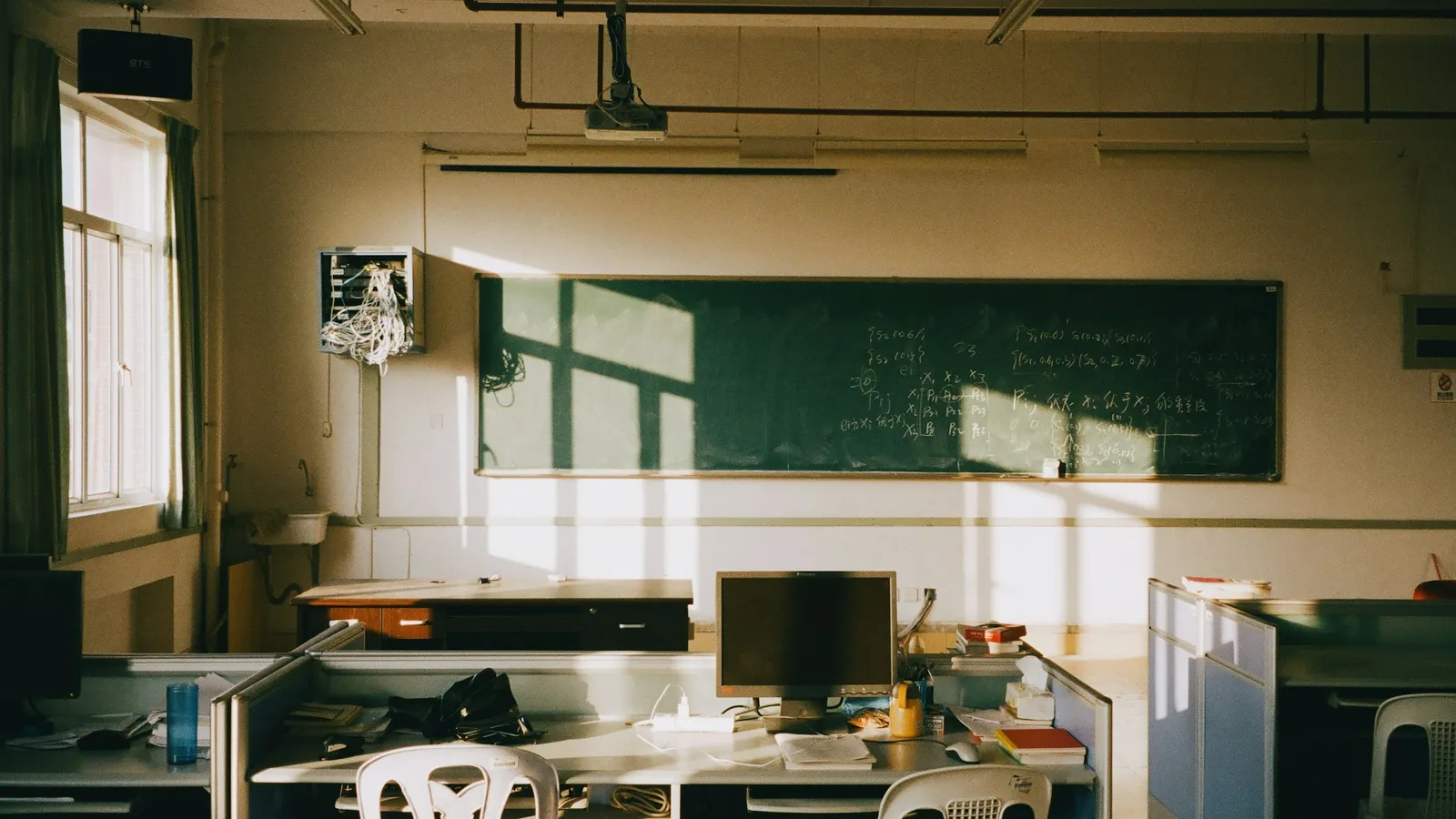 An empty classroom with desks facing a green board