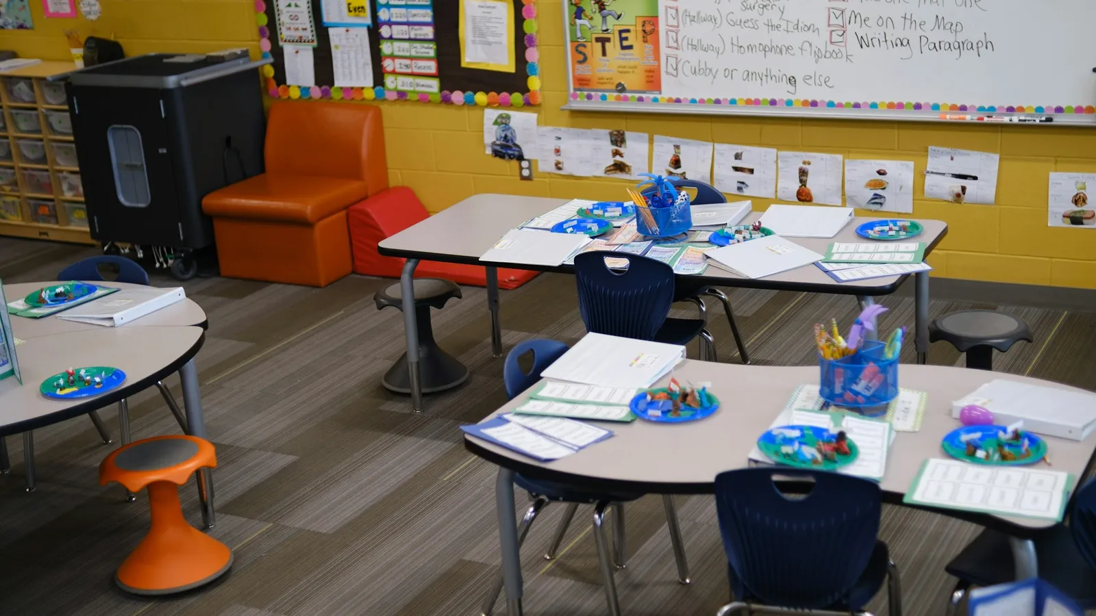 An empty classroom with small desks, chairs and colourful wall displays