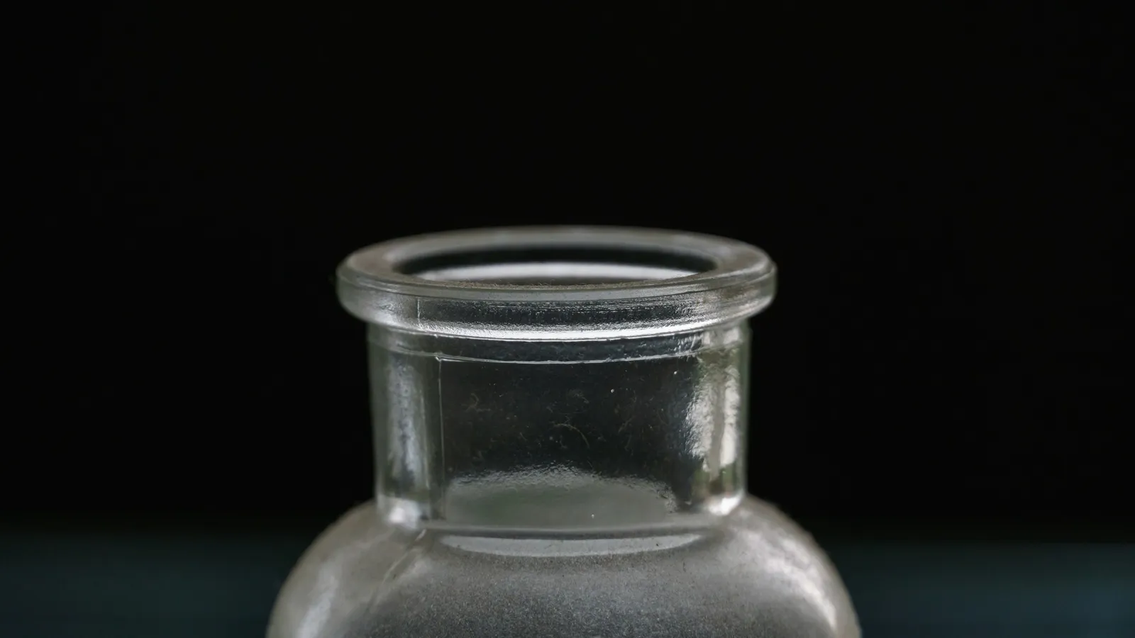 An empty glass reagent jar on black