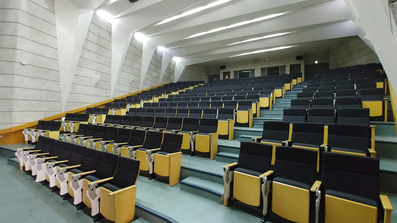 An empty tiered lecture hall with rows of seats