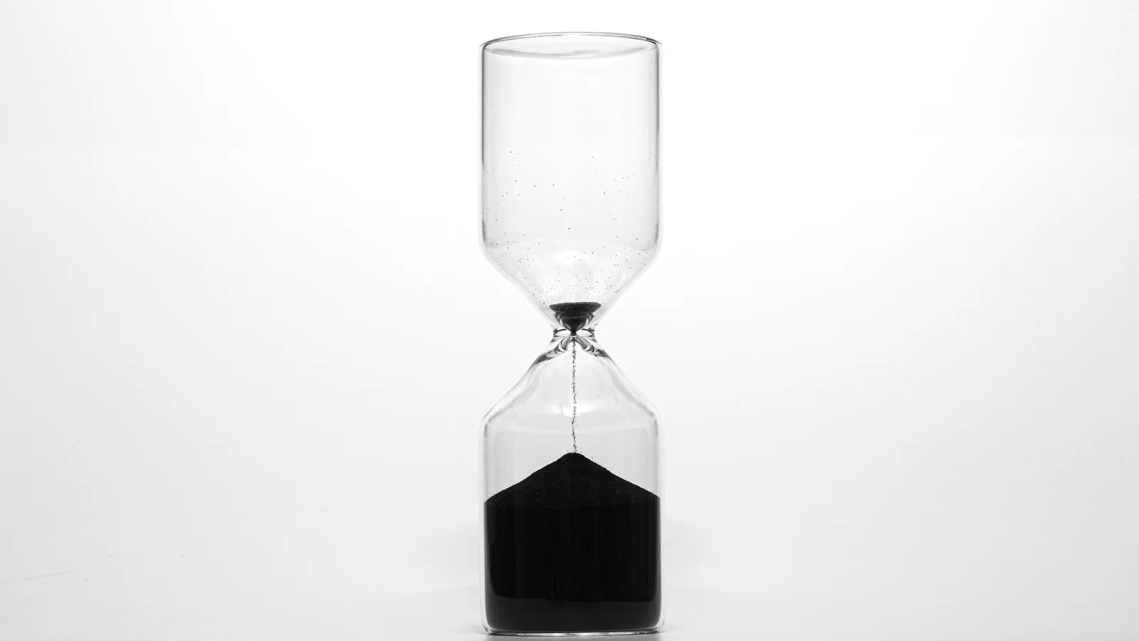 An hourglass with dark sand on a white background