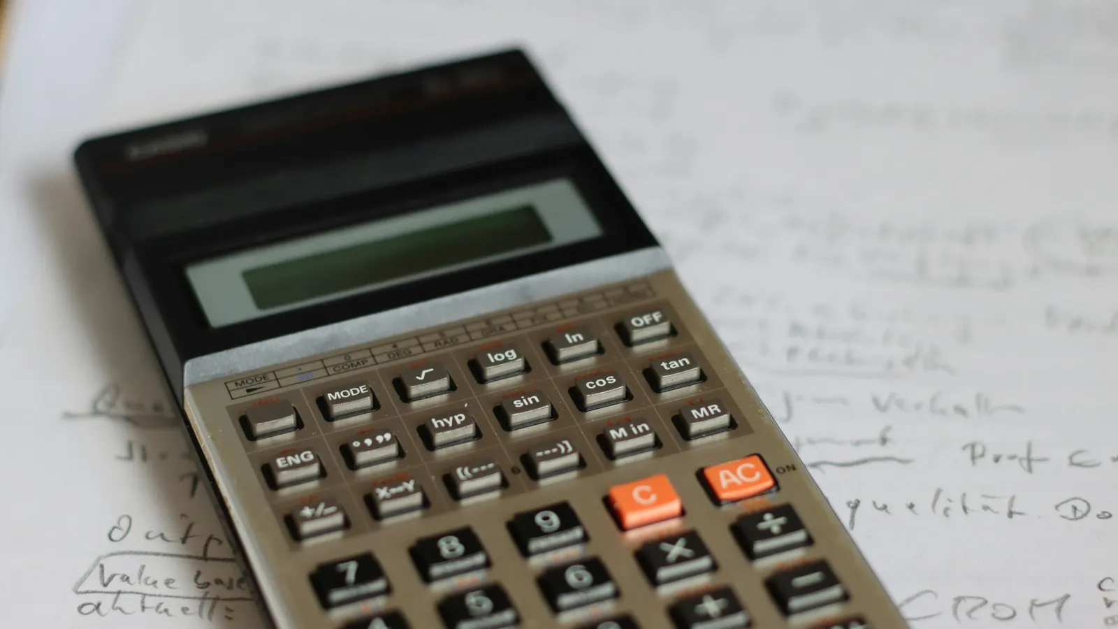 An old calculator lying on pages of handwritten calculations