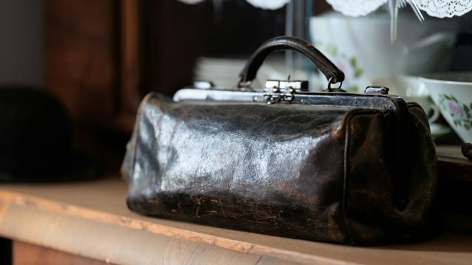 An old leather doctor bag on a wooden shelf