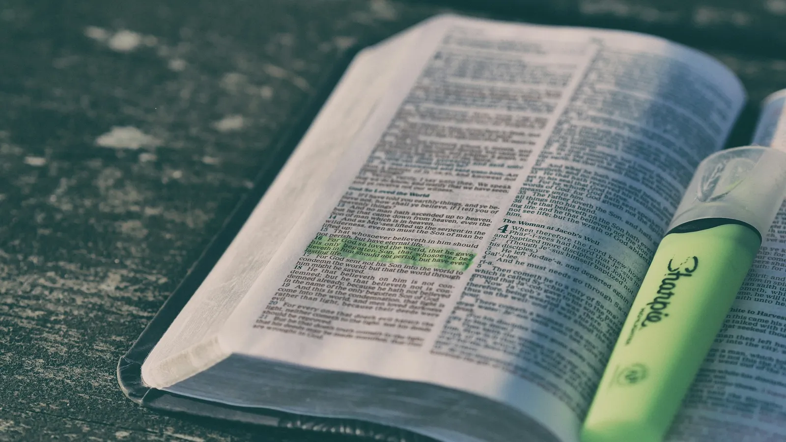 An open book with a green highlighter resting on it