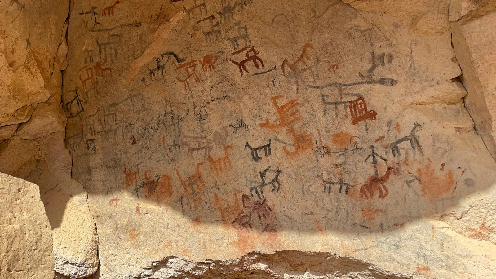 Ancient rock paintings of people and animals on a cave wall