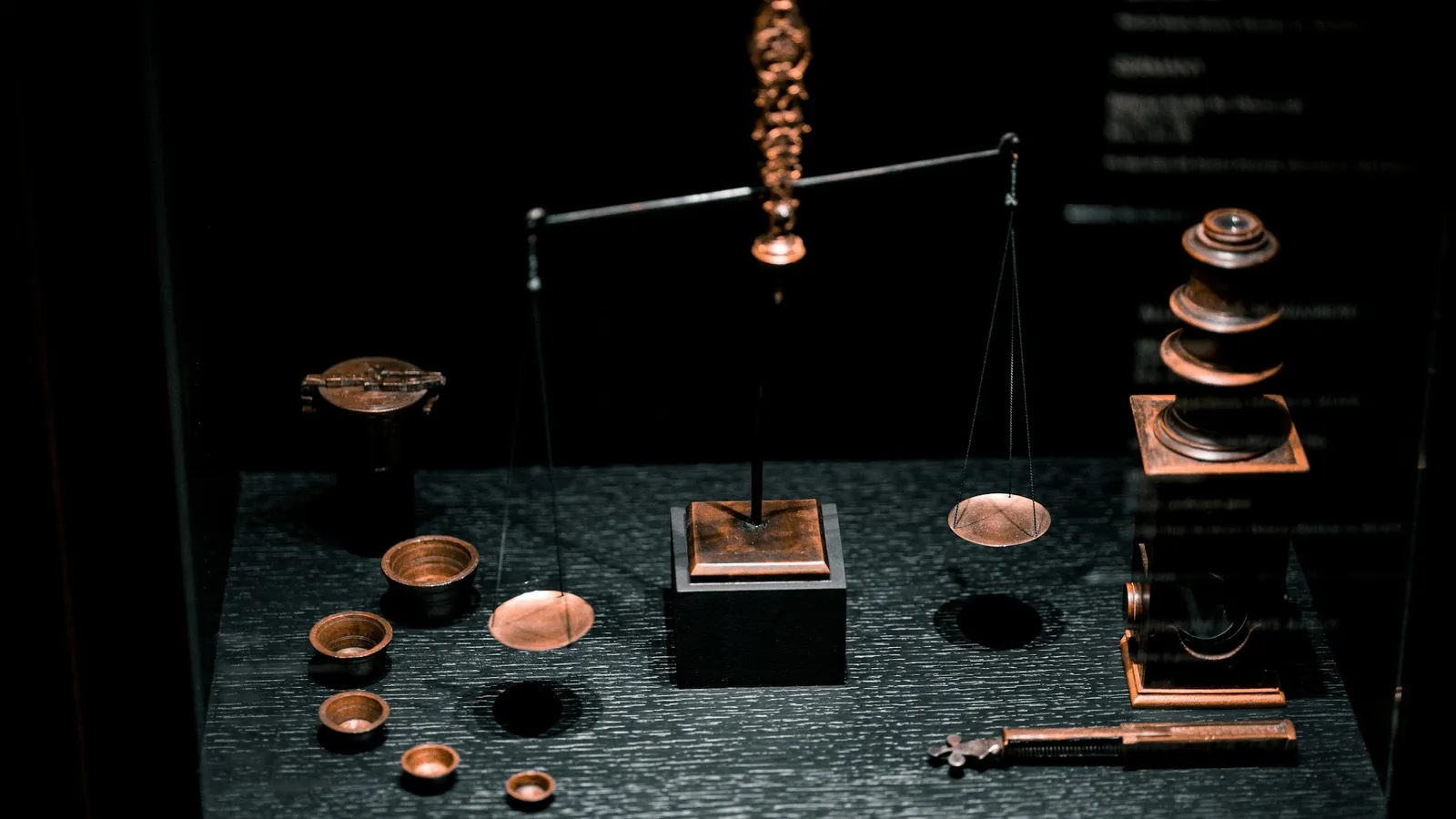 Antique brass weights and a balance on a dark table