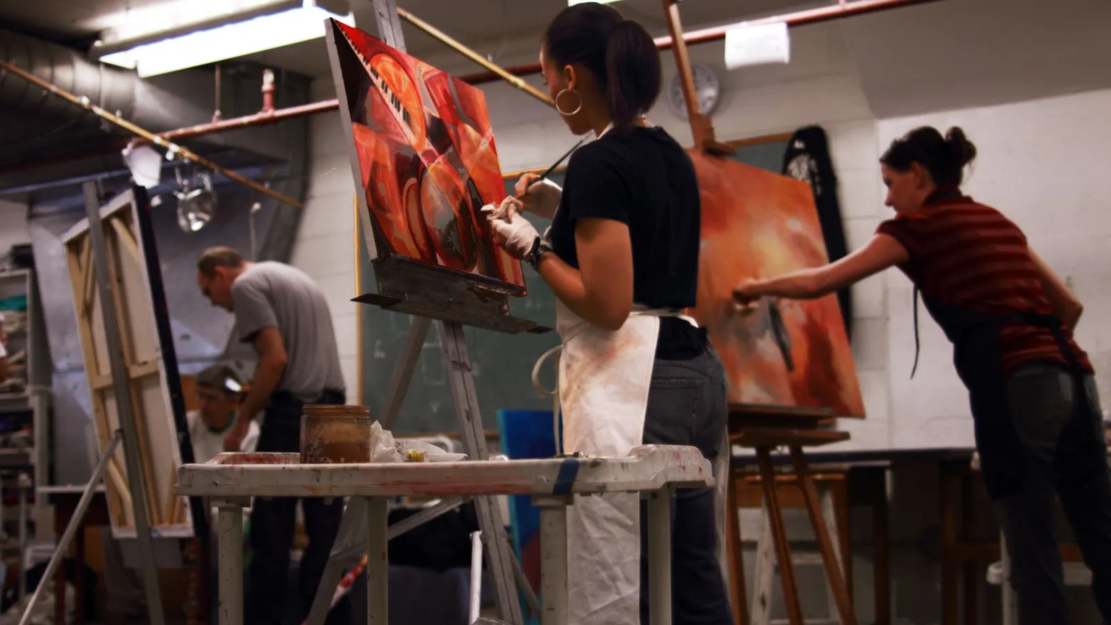Art students painting large canvases at easels in a studio