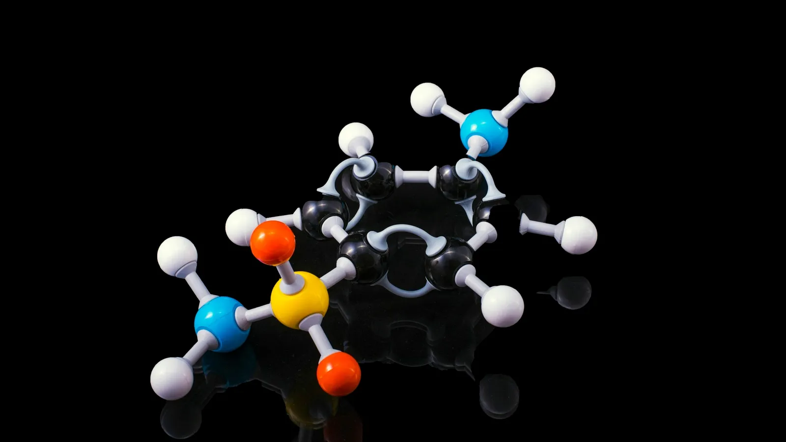 Ball-and-stick molecular model with coloured atoms on a black background