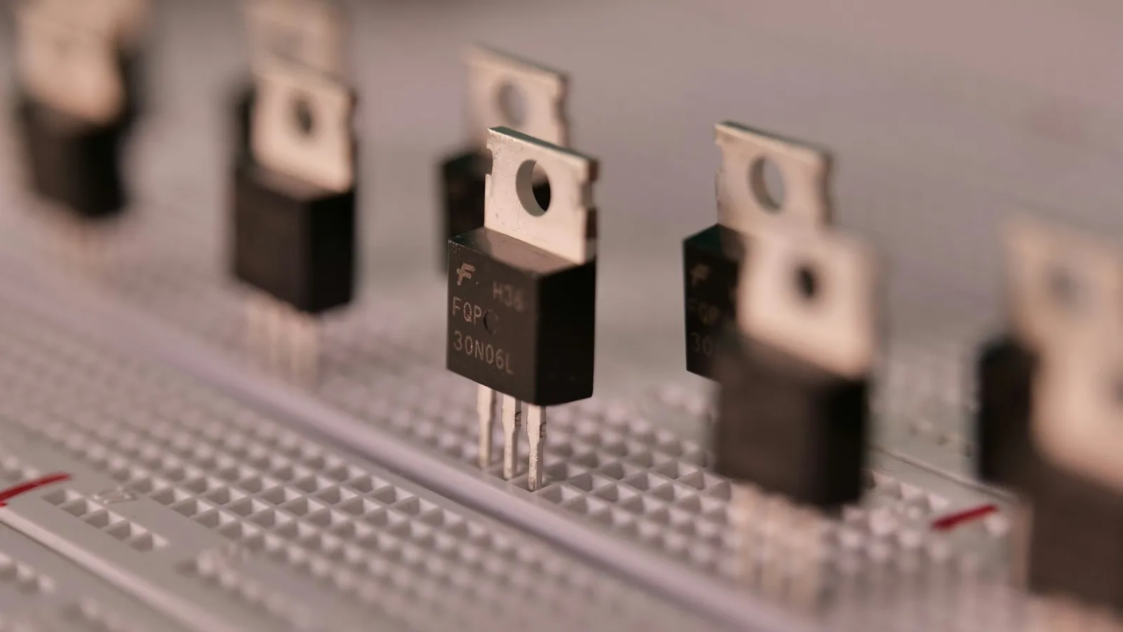 Black transistors with metal tabs mounted on a breadboard