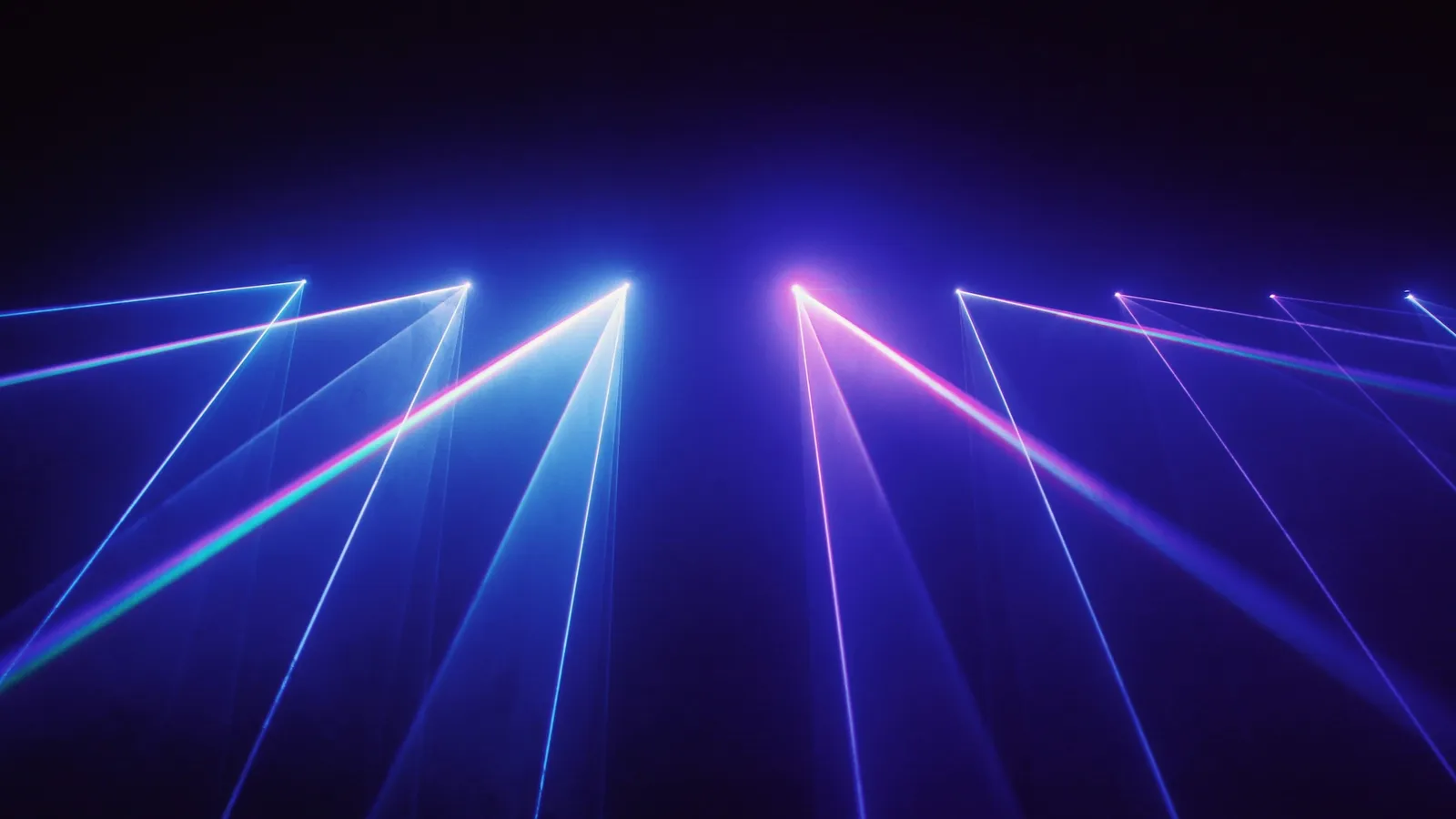 Blue and purple laser beams fanning out in the dark