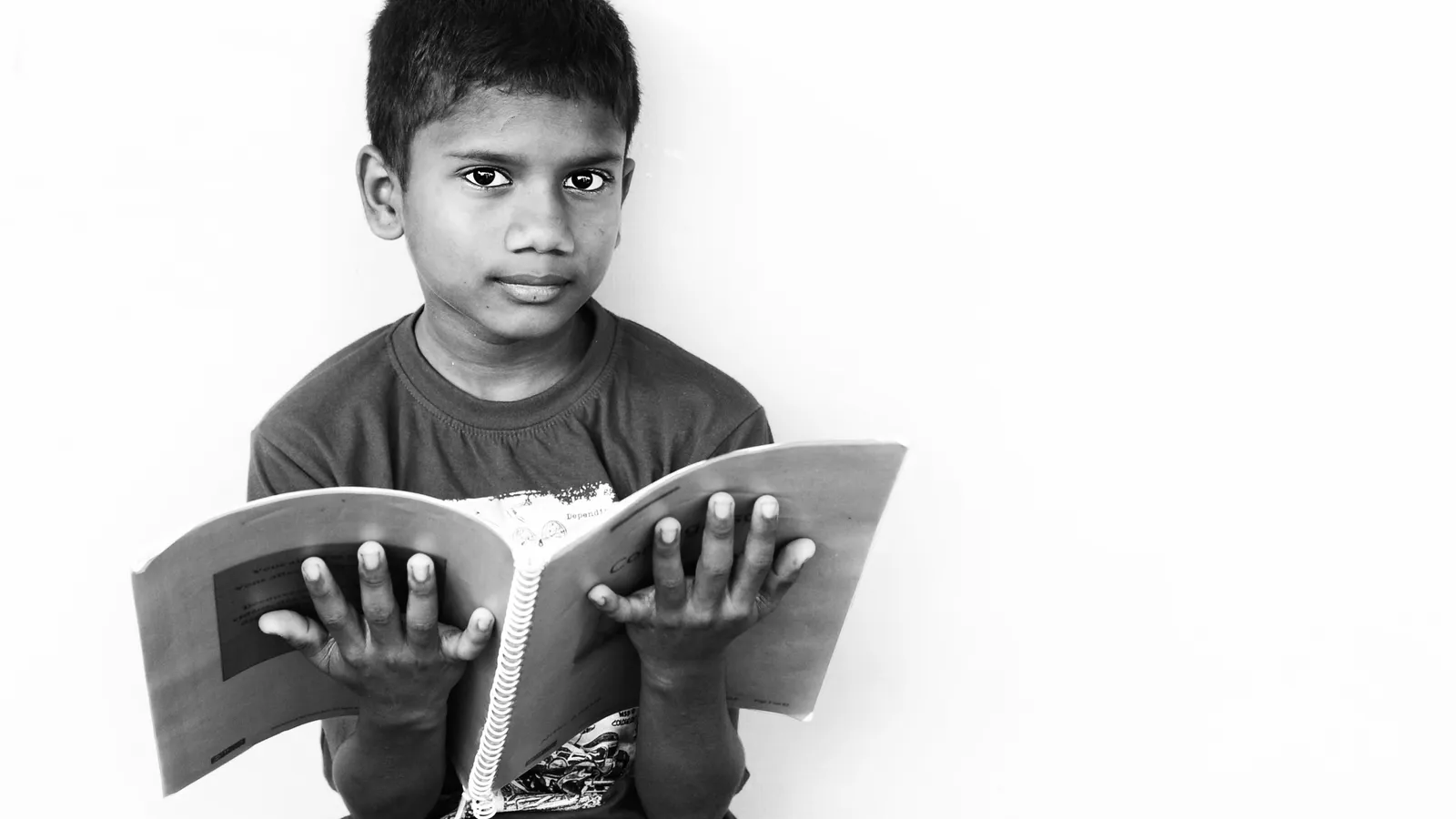Boy holding an open spiral-bound book, black and white photo