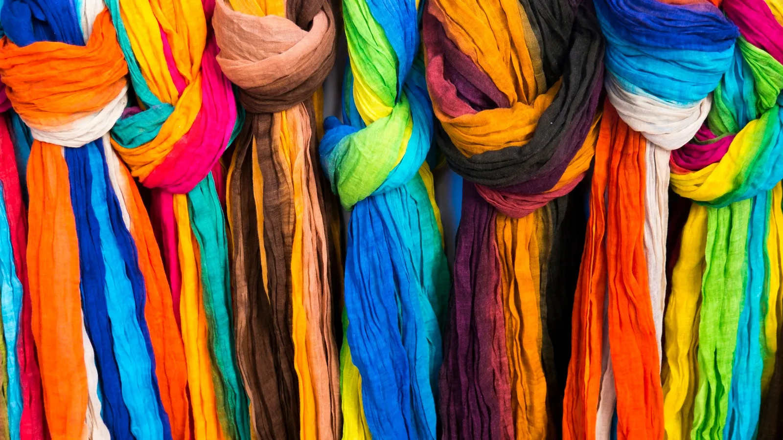 Brightly dyed scarves hanging in rows