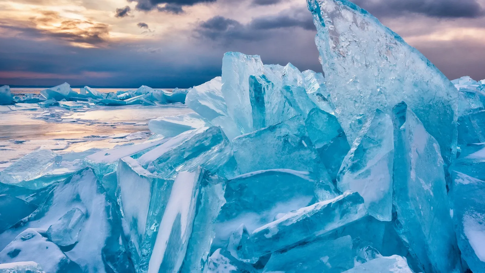 Broken sheets of blue ice piled up on a frozen lake