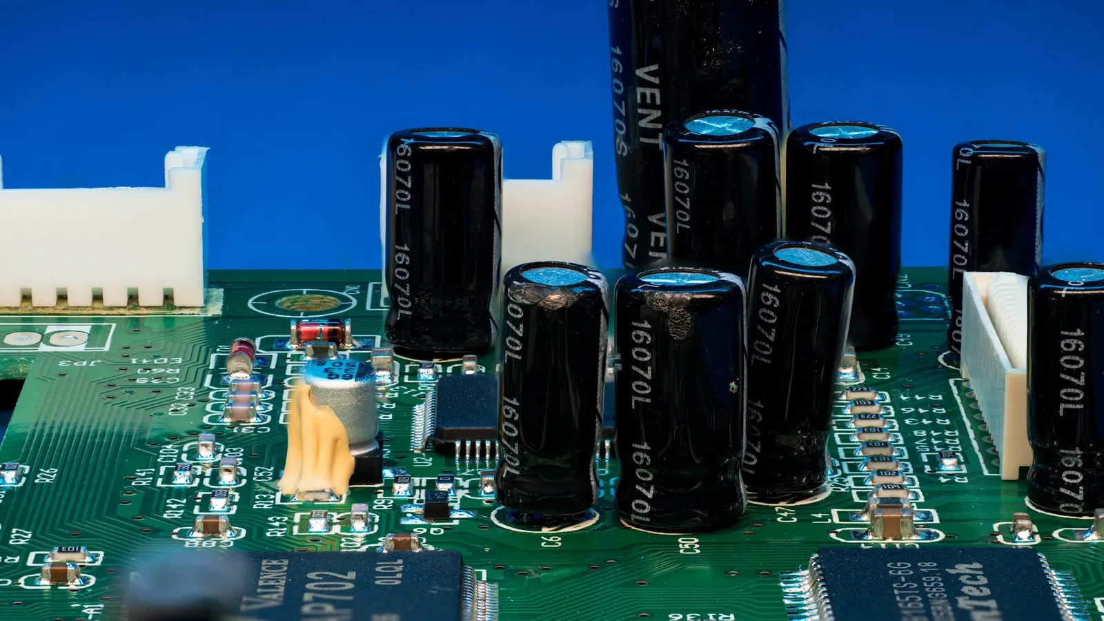 Capacitors standing on a circuit board against a blue background