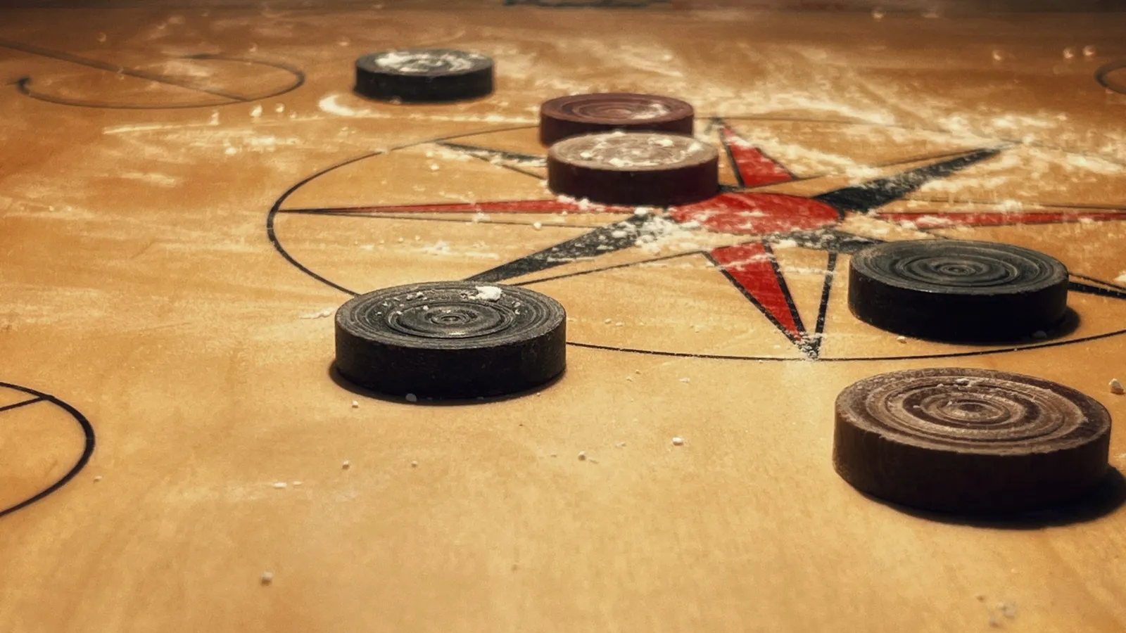 Carrom pieces scattered across a carrom board