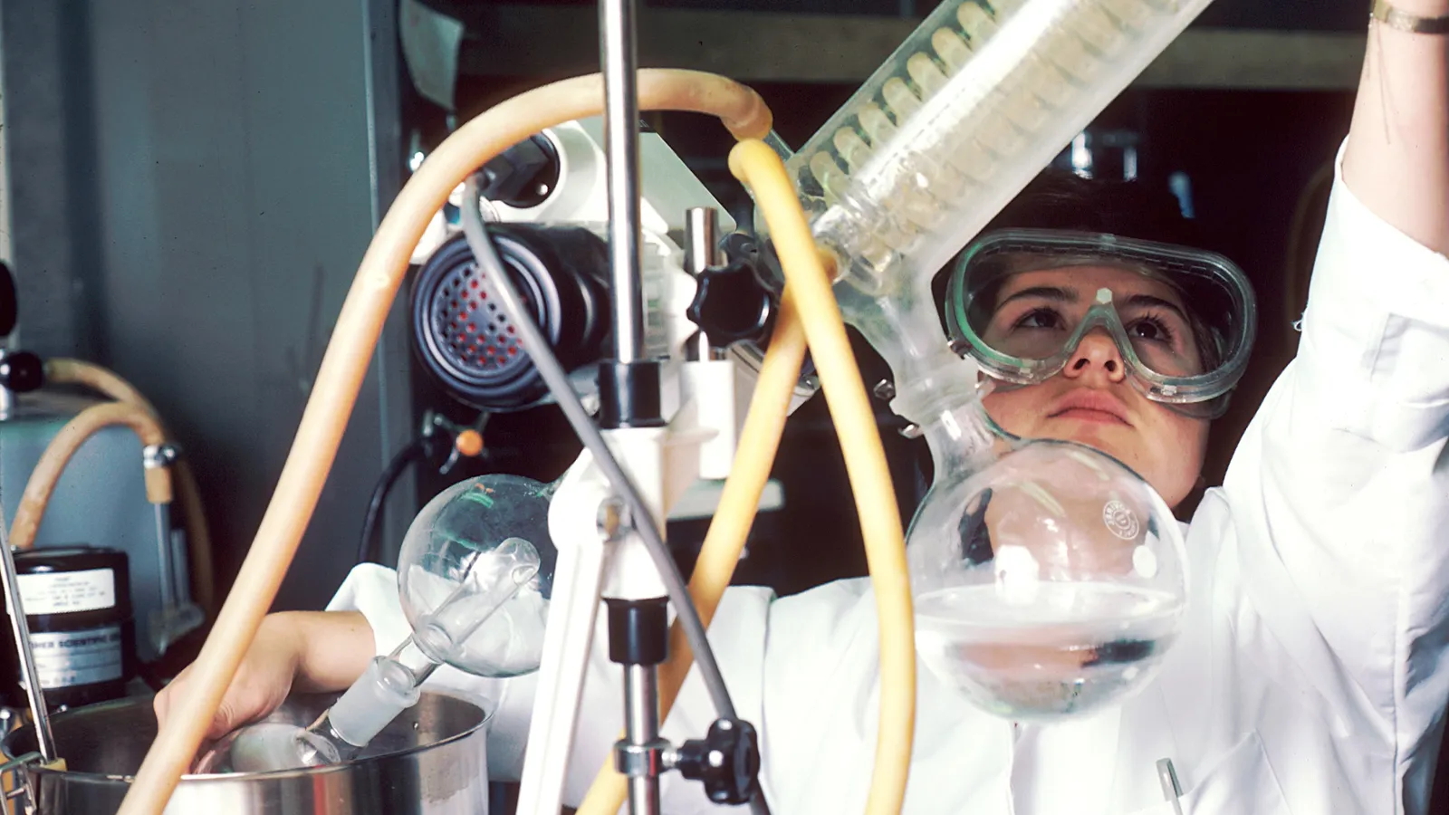 Chemist in goggles removing a flask from a rotary evaporator in a lab