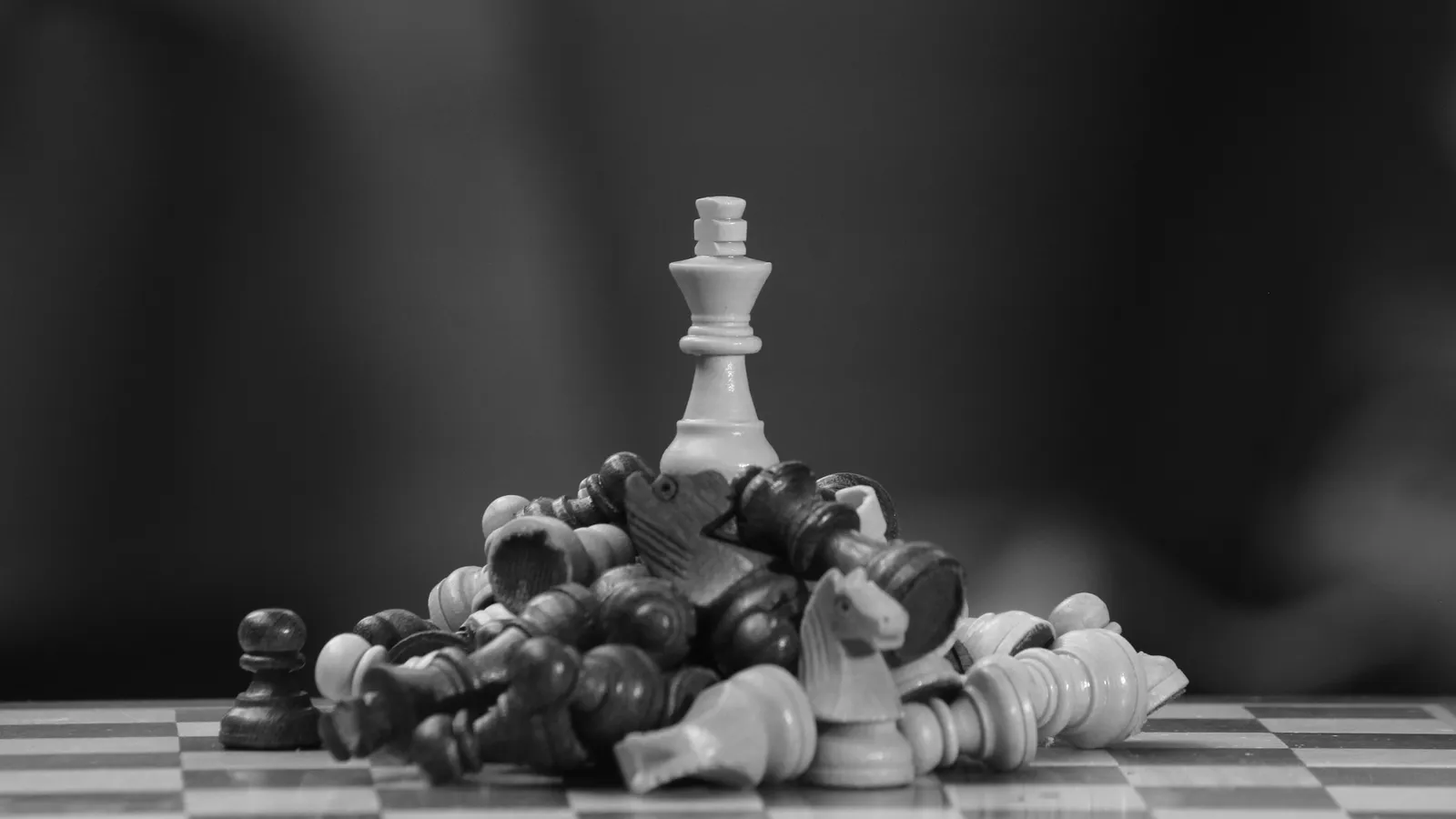 Chess king standing among fallen pieces