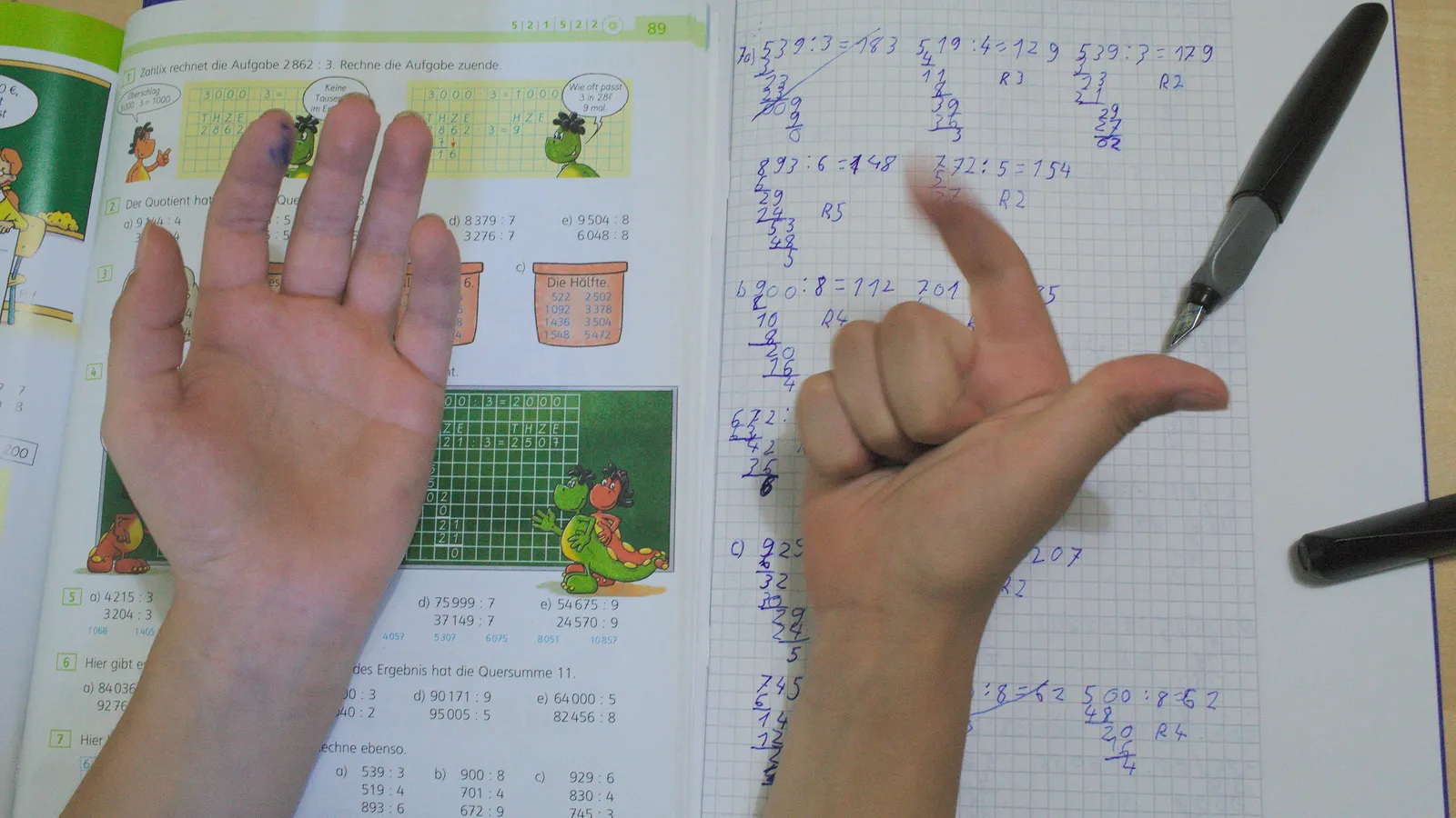 Child counting on fingers beside handwritten long-division working in a squared notebook