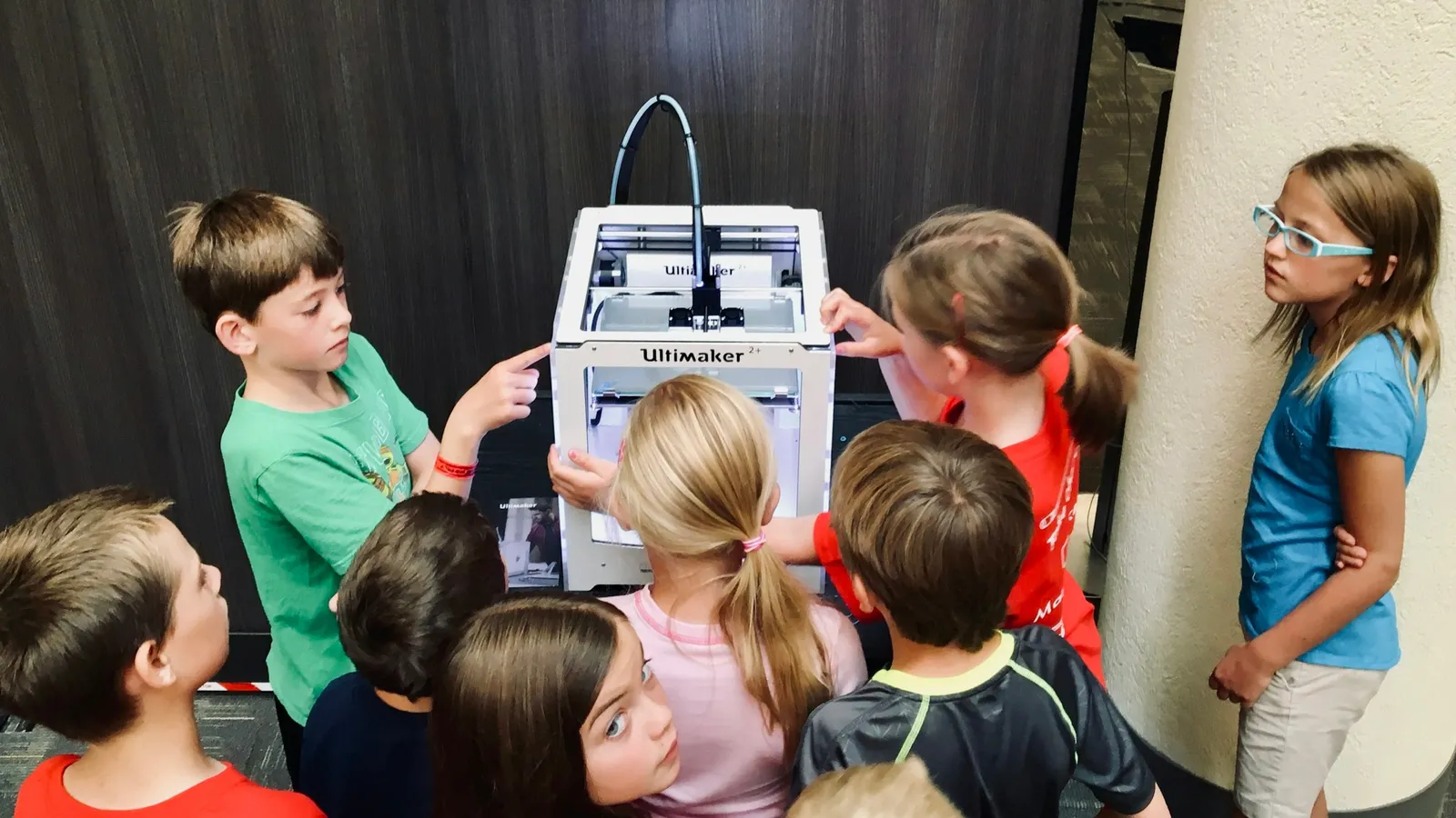 Children gathered around a 3D printer