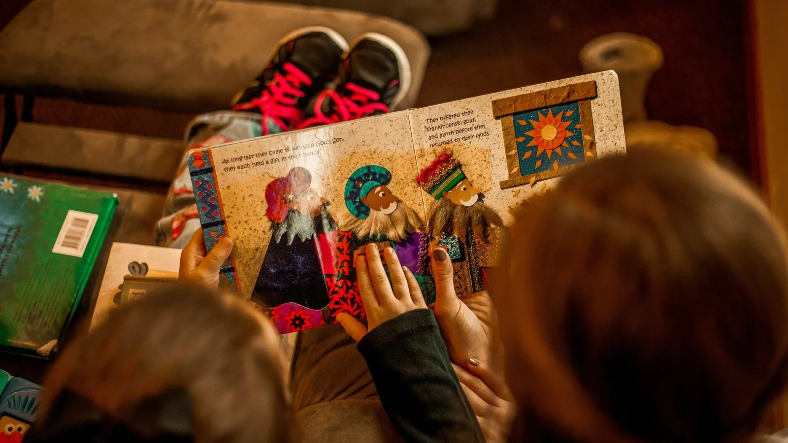 Children looking at an illustrated picture book together, seen from above
