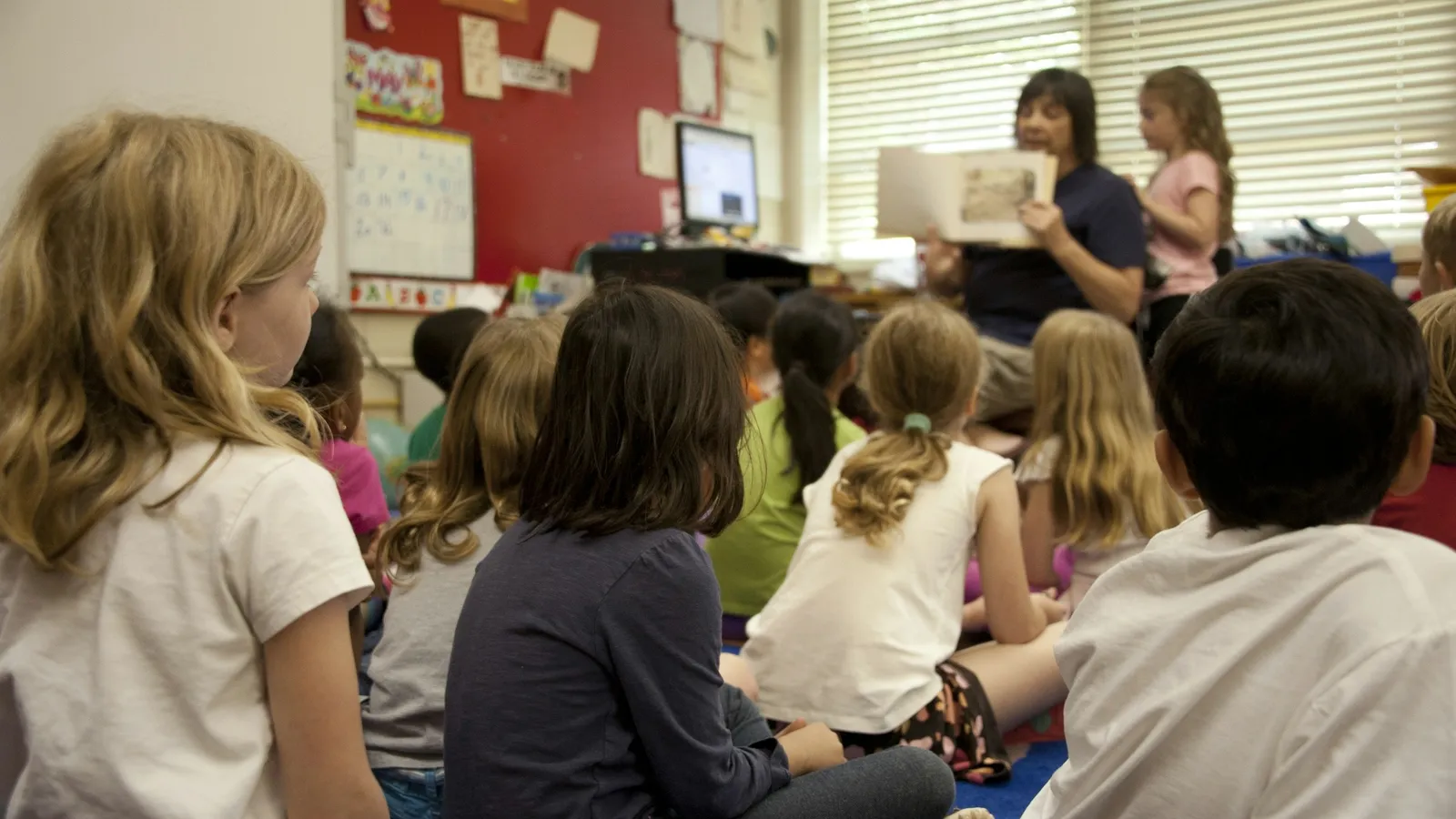 Children sitting on a classroom floor listening to a story