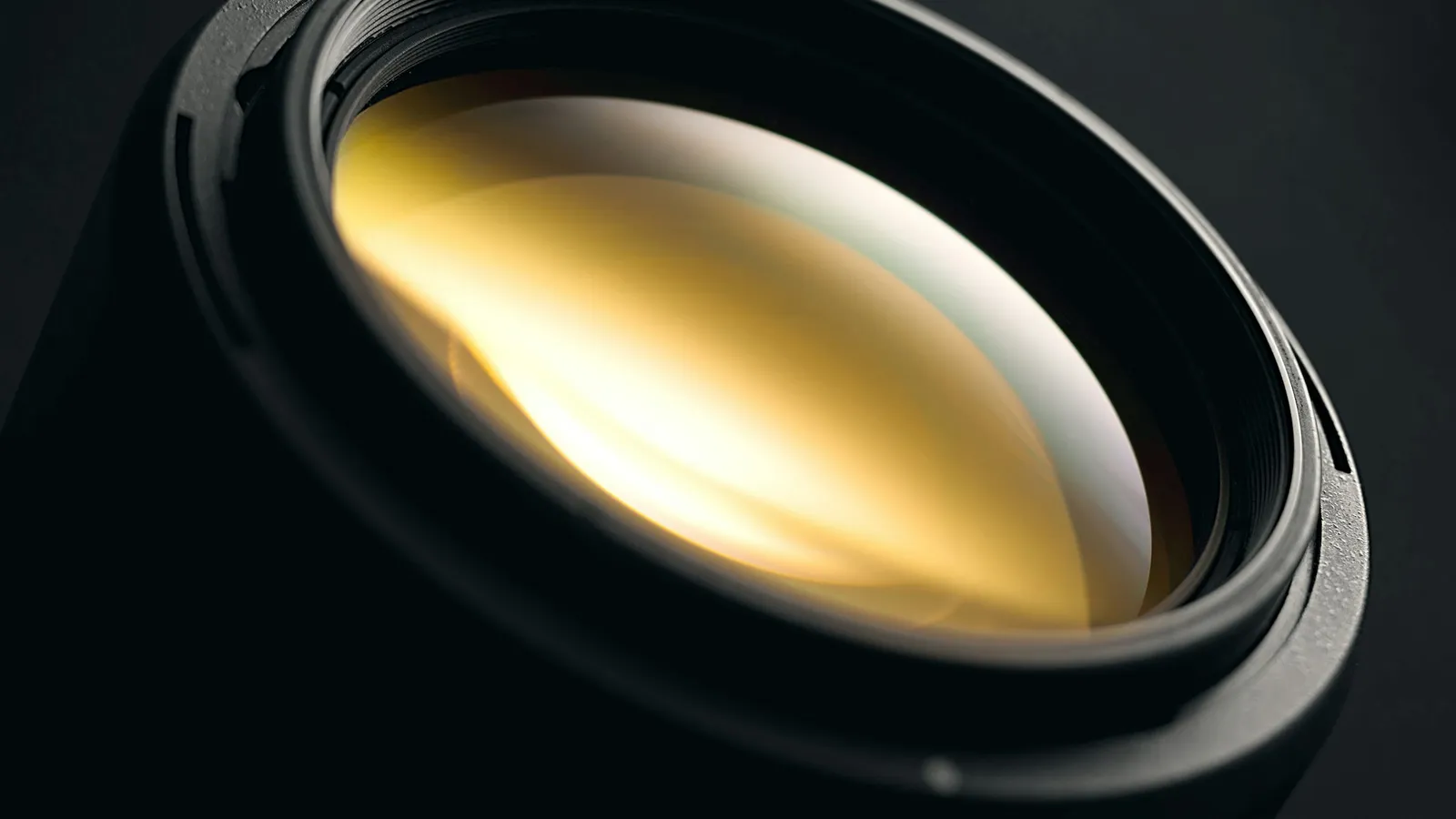 Close-up of a glass camera lens element catching the light